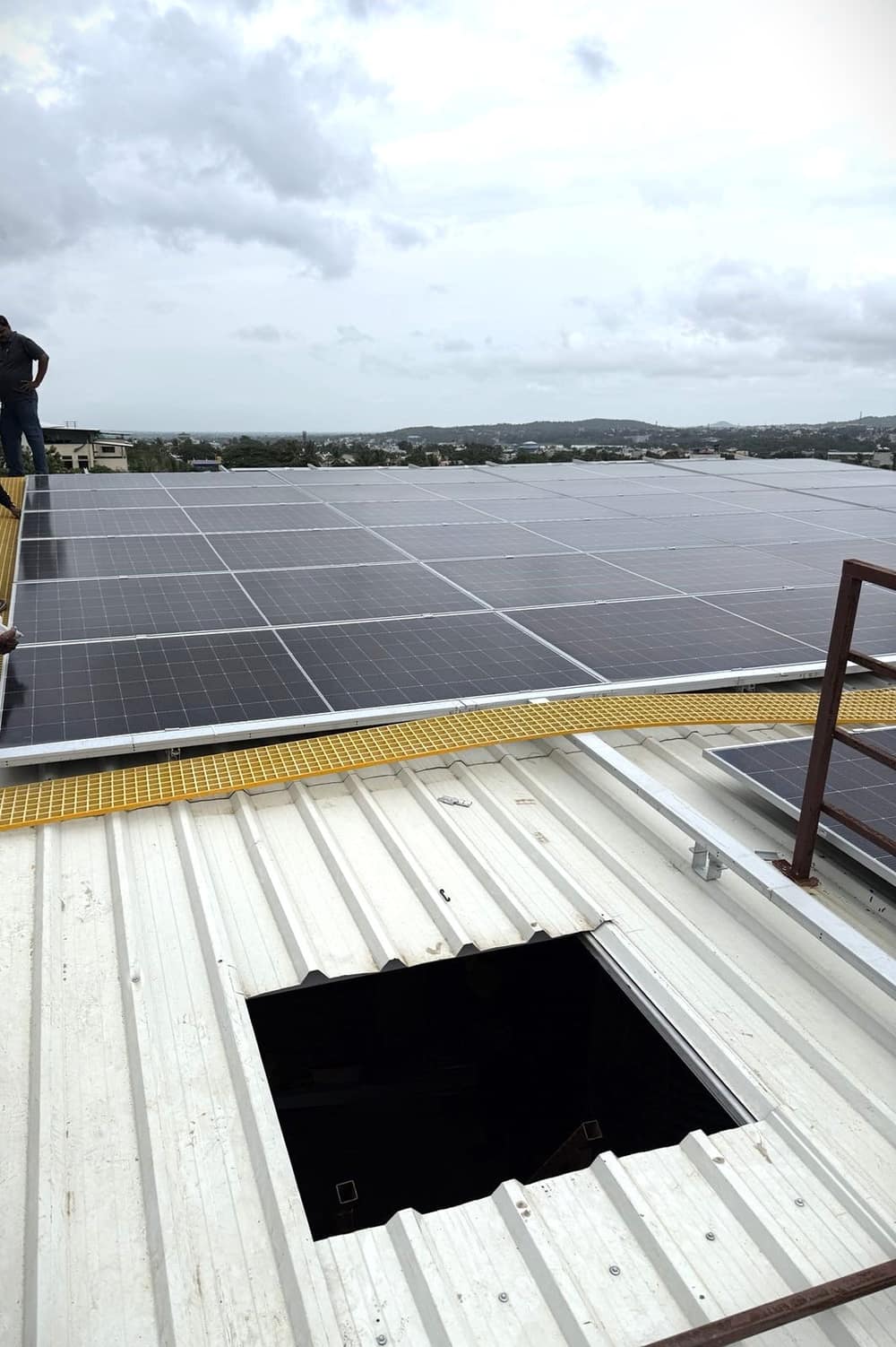 Large rooftop solar array covering an industrial shed roof, with a walkway between the rows